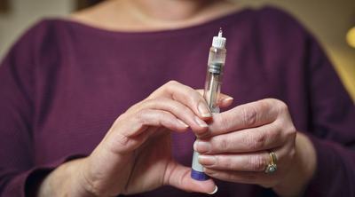 Female senior holding GLP-1 syringe.