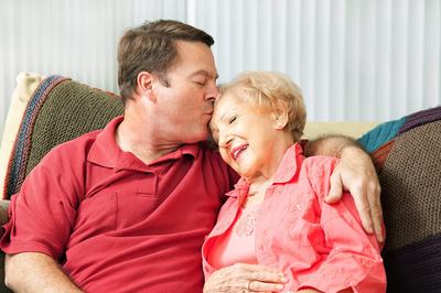 Adult son kisses his senior mother on the head
