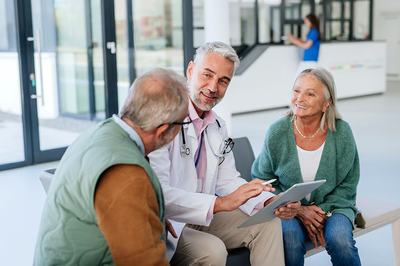 Concierge medicine doctor with elderly couple reading a chart.