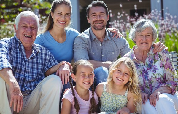 Family of three generations smiling in front of their house