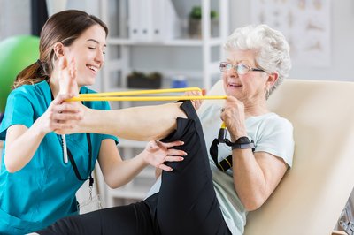 A female physical therapist with a female senior doing exercises.