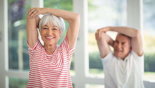 A female and male senior doing arm stretches