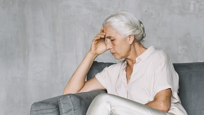 Depressed senior sitting on the couch.