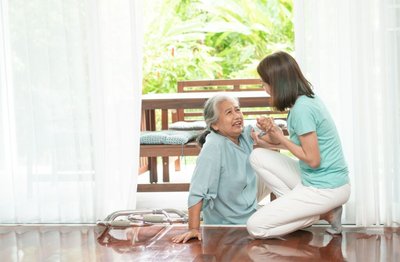 Senior laying on the ground after a fall and daughter helping her up.