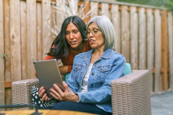 Senior female with adult daughter in front of a computer.