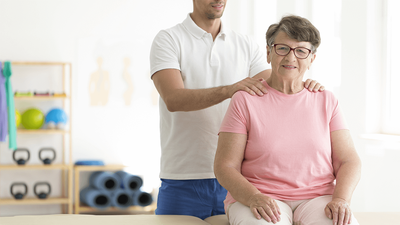 Trainer helping senior with Hyperkyphosis