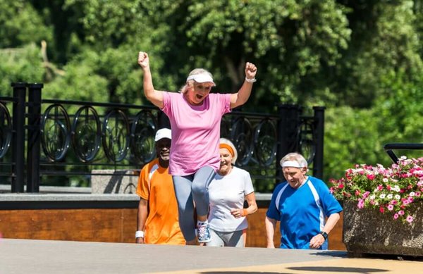 Four seniros outdoors coming up steps on a sunny day